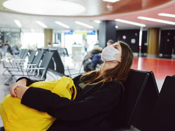 Женщина с закрытыми глазами в медицинской маске ждет полета в аэропорту — стоковое фото