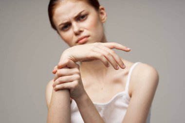 Beyaz tişörtlü kadın kol ağrısı, artrit, kronik hastalık, hafif arka plan.