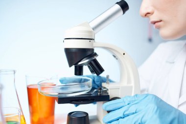 Masada oturan bayan doktor mikroskop araştırma ışık arka planı