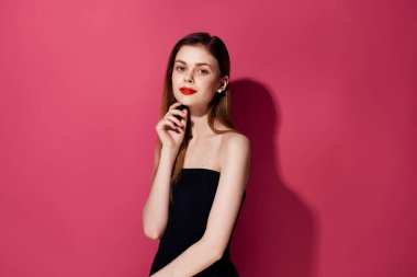 Siyah elbiseli güzel bir kadın pembe arka planda.