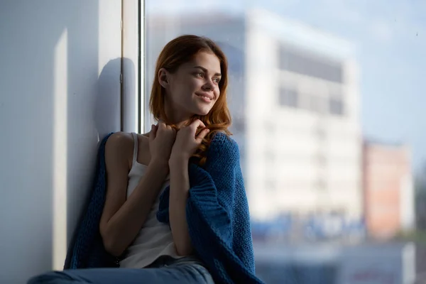 Kvinna sitter nära fönstret med en blå rutig drömmande utseende — Stockfoto