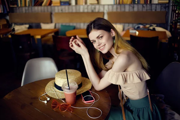 Mujer alegre sentada en una mesa con una bebida en un café comunicación — Foto de Stock