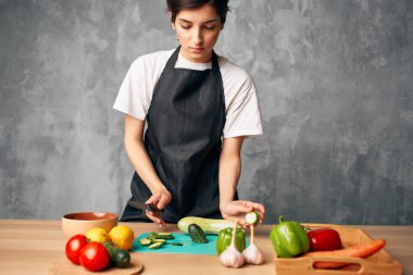 Mutfaktaki ev hanımı izole edilmiş sebzeleri kesiyor.