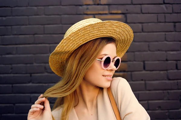 Beautiful woman on the street wearing hat and glasses black brick wall city trip — Stock Photo, Image