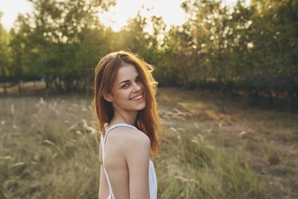 Glad söt kvinna i en vit klänning i en grön gräsplan promenader — Stockfoto