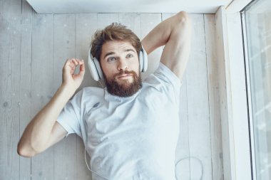 Kulaklık takan genç bir adam pencere eşiğinde yatıyor.