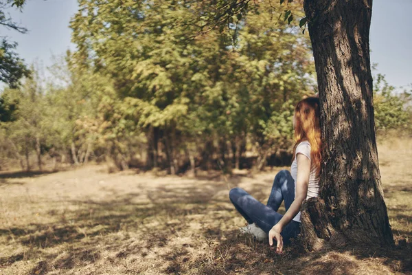 Симпатичная женщина, сидящая у дерева — стоковое фото