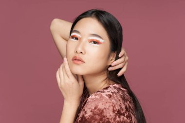 Yüzünde makyaj olan Asyalı kadın saçlarını düzleştiriyor.