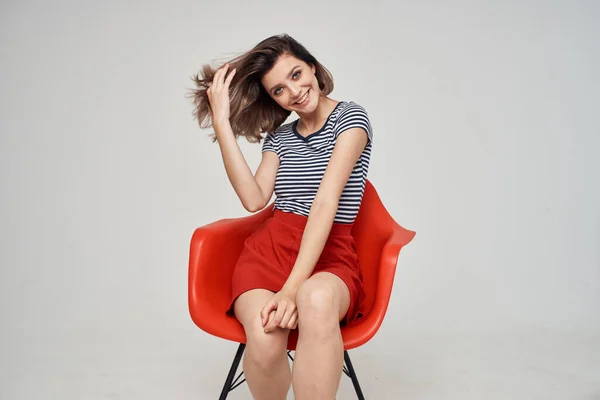 Vacker kvinna i fashionabla kläder sitter på den röda stolen — Stockfoto