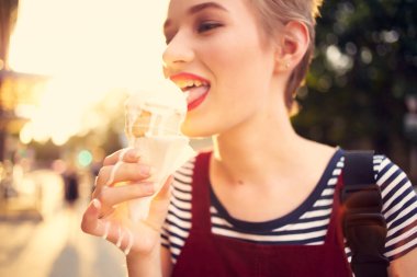 Kısa saçlı, açık havada dondurma yiyen bir kadın.