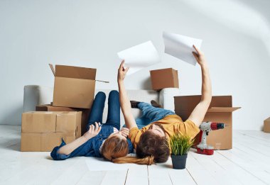Kadın ve erkek, kutularla dolu bir dairede tadilat yapıyorlar.