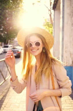 Güneş gözlüğü takan neşeli kadın yaz tatilinde dışarıda yürüyor.