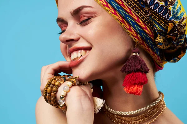 Glad kvinna i flerfärgad turban attraktiv utseende smycken leende blå bakgrund — Stockfoto