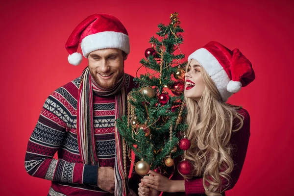 Glada unga par nytt år träd dekoration röd bakgrund — Stockfoto