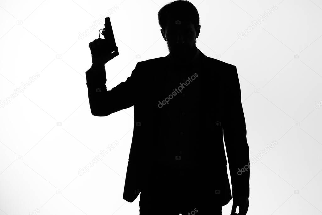 The man in a suit Secret agent with a gun in the hands of a crime posing studio