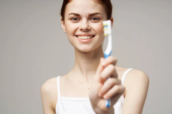 Pretty woman with a toothbrush in hand morning hygiene light background — Stock Photo, Image