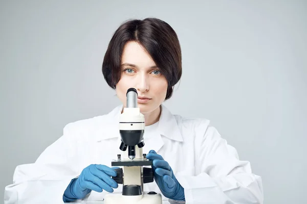 Kadın laboratuvar asistanı mikroskop ile teşhis araştırması yapıyor. — Stok fotoğraf