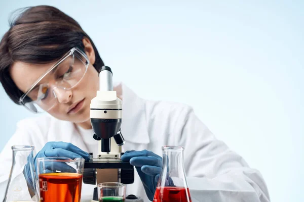 Feminino médico sentado à mesa microscópio pesquisa biotecnologia isolado fundo — Fotografia de Stock