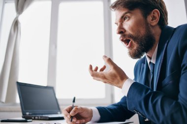 Bir dizüstü bilgisayarın önünde oturan sakallı bir adam.