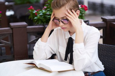 Elinde kitapla gezen bir öğrenci. Şehir içinde gezip eğleniyor.