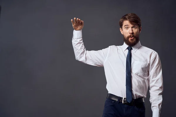 The man in a suit in a white shirt pulls the tie dark background