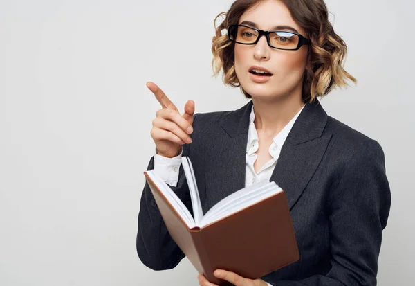 Donna in giacca e cravatta con un libro in mano sfondo chiaro — Foto Stock