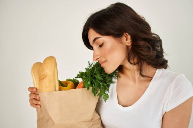 Bir paket erzağı olan bir kadın sağlıklı yiyecekler getiriyor.