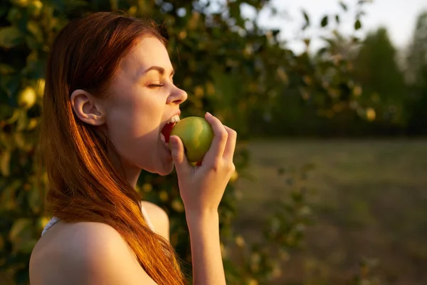 漂亮的女人穿着白衣，手拿着苹果，是天生的水果 — 图库照片