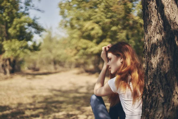 Симпатичная женщина, сидящая у дерева. — стоковое фото
