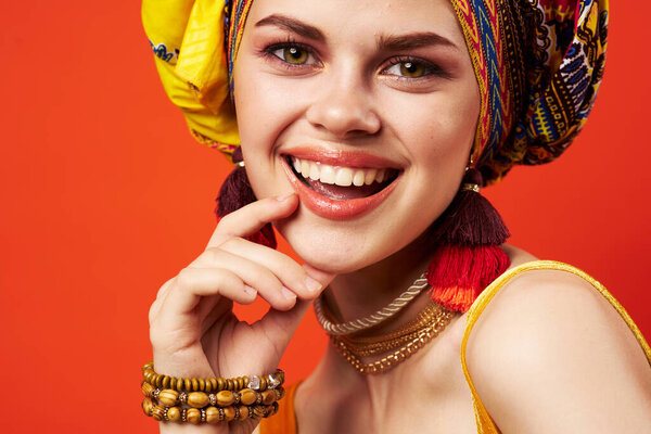 Cheerful woman ethnicity multicolored headscarf makeup glamor red background. High quality photo