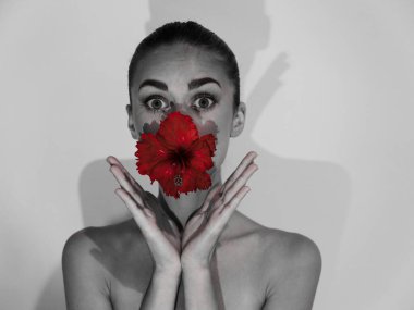 Ağızda çiçek tutan çıplak omuzlu güzel bir kadın. Kırpılmış görüntü gri fotoğraf.