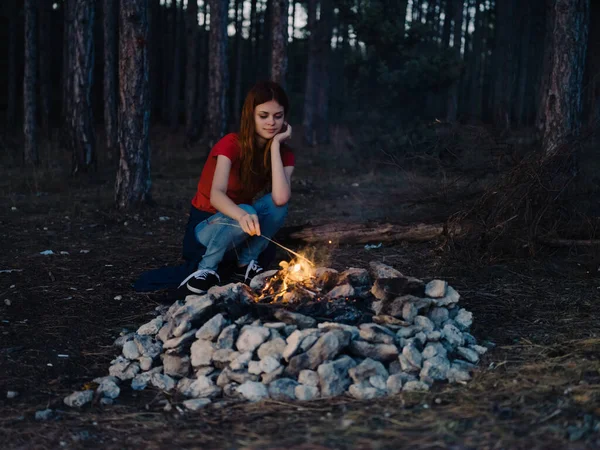 Mujer sentada cerca de la noche de vacaciones fogata en el viaje por el bosque —  Fotos de Stock