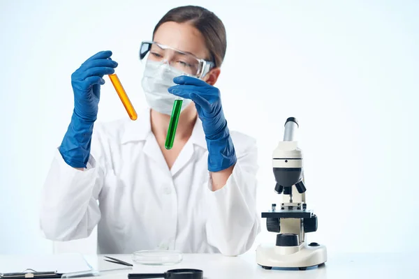 Žena laboratorní asistentka nošení žluté brýle chemické řešení mikroskop výzkum biotechnologie — Stock fotografie