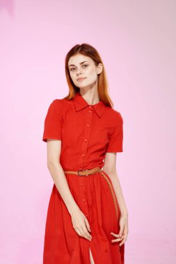 Kırmızı elbiseli, zarif, pembe arka planlı güzel bir kadın.