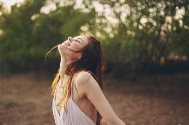 Açık havada beyaz elbiseli neşeli kadın özgürlük yürüyüşü yapıyor.