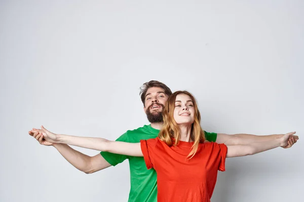 Una joven pareja multicolor camisetas comunicación disputa luz fondo — Foto de Stock