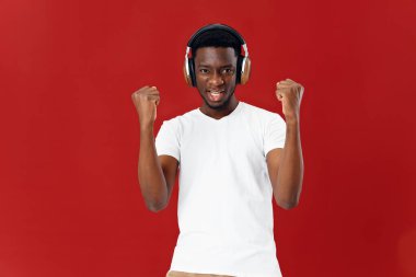 Afrika kökenli bir adam kulaklıklı kırmızı arka planlı.
