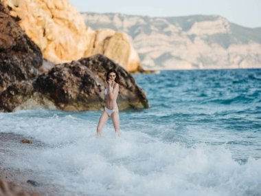 Beyaz mayo giymiş bir kadın bir dağ manzarası boyunca yürür. Temiz hava.