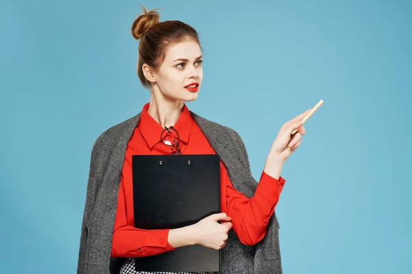 Mulher em uma camisa vermelha com uma jaqueta detém uma folha de papel Copiar Espaço azul fundo — Fotografia de Stock
