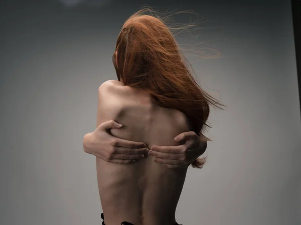 Rödhårig kvinna som håller händerna bakom ryggen visa figur — Stockfoto