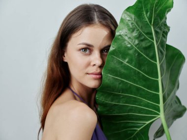 Çıplak omuzlu kadın yeşil yapraklı tropik kuşaklar