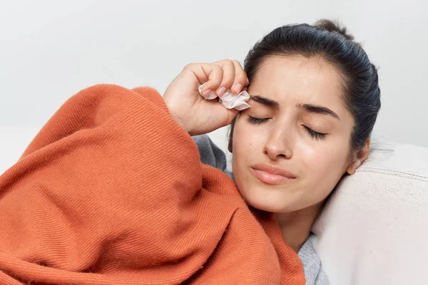 毛布に覆われた冷たい健康上の問題で覆われたソファに寝そべっている女性 — ストック写真
