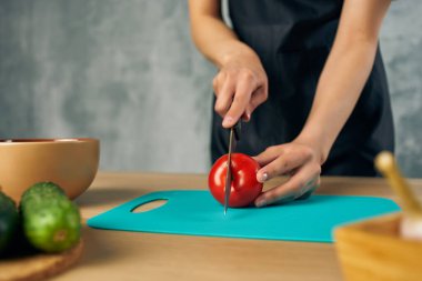 Mutfakta siyah önlüklü aşçı Sebze kesme tahtası