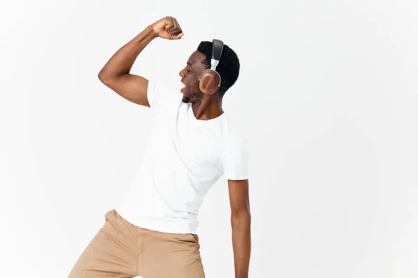 Hombre de apariencia africana en auriculares con una camiseta blanca escucha música — Foto de Stock