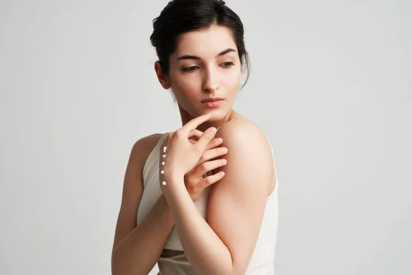 Mulher em um creme de t-shirt branco em suas mãos Saudável pele luz fundo — Fotografia de Stock