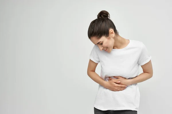 Bruna in t-shirt bianca che tiene le mestruazioni del ventre problemi di salute insoddisfazione — Foto Stock