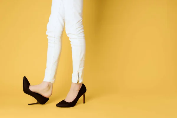Piernas femeninas invertidas en zapatos negros posando fondo amarillo — Foto de Stock