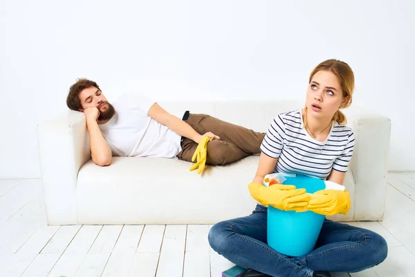 A young couple near the sofa cleaning supplies light background — Stock Photo, Image