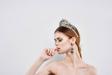 Kafasında taç olan güzel bir kadın. Makyaj modeli, hafif arka plan.
