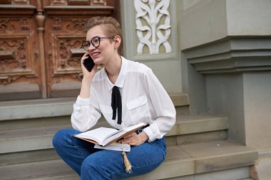 Elinde kitap olan güzel bir kadın dışarıda iletişim kuruyor.